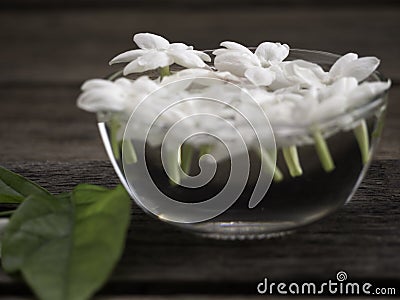 Jasmine floating in clear glass on wooden background Stock Photo