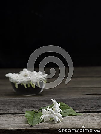 Jasmine floating in clear glass on wooden background Stock Photo