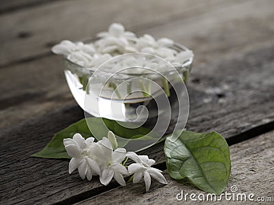 Jasmine floating in clear glass on wooden background Stock Photo