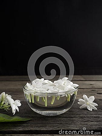 Jasmine floating in clear glass on wooden background Stock Photo