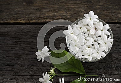 Jasmine floating in clear glass on wooden background Stock Photo