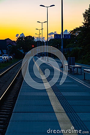 Beautiful cloudy sunset over long train platform with few people at waiting for train to come Editorial Stock Photo