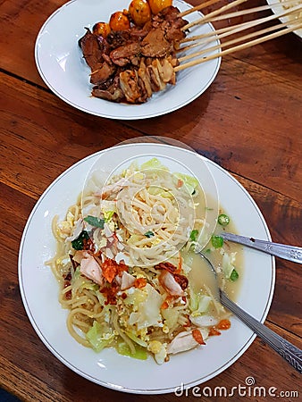 Javanese boiled noodles with shredded chicken, eggs, vegetables and grilled chicken satay Stock Photo