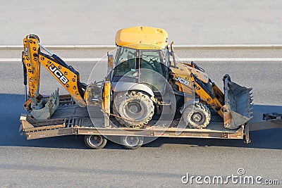 JCB 3CX machinery a tractor bucket back and front for digging is transported trailer platform truck highway. Russia, Saint- Editorial Stock Photo