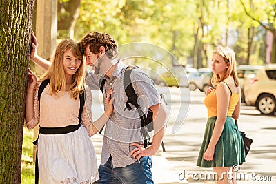 Jealous girl looking at flirting couple outdoor. Stock Photo