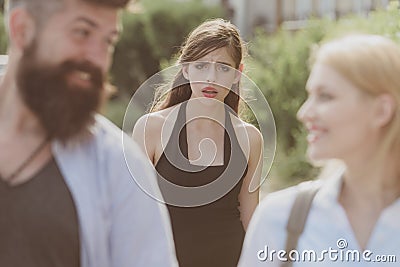 She is the jealous type. Jealous woman look at couple in love on street. Unhappy girl feeling jealous. Romantic couple Stock Photo