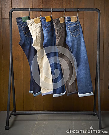 Jeans hanging on a rack with a wooden background Stock Photo