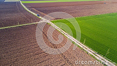 A jeep crossing a country road, off-road aerial view of a car traveling a dirt road through the fields. Stock Photo