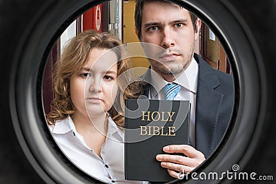 Jehovah witnesses are showing bible behind door. View from peephole Stock Photo