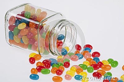 Jelly Beans candy spilled from glass jar on white backg Stock Photo