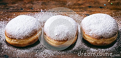 Krapfen with powder sugar, three and isolated on wooden background. Stock Photo
