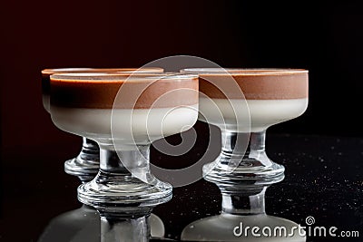 Jelly in glass cup on black background. Vases are reflected in a black glass background. Stock Photo