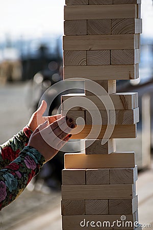 Jenga, girl`s hands try to pull out a wooden block, without tipp Stock Photo