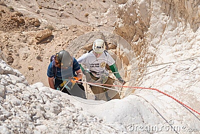 Young athletes start pair downhill using snapping gear in the mountains of the Judean Desert near the Tamarim stream near Editorial Stock Photo