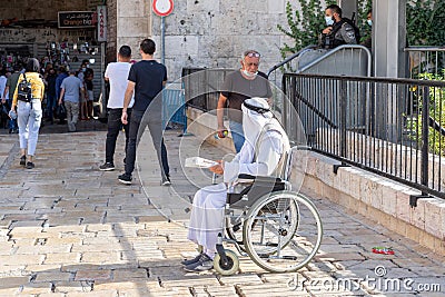 An elderly Muslim Arab sits near the Damascus Gate and begs for alms in the Muslim part of the old city of Jerusalem, Israel Editorial Stock Photo