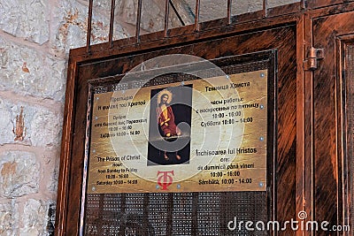 The sign with opening hours on the door of the Prison of Christ in the Greek Orthodox monastery on Via Dolorosa Street in the old Editorial Stock Photo