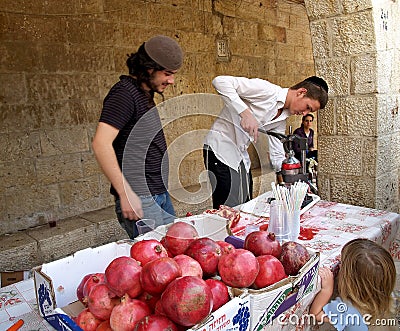 JERUSALEM, ISRAEL. Young people wring out and sell garnet juice on the street Editorial Stock Photo
