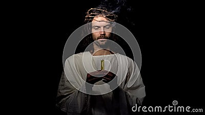 Jesus Christ holding blown candle, praying for people sins expiation, salvation Stock Photo