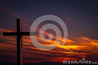 Jesus Christ wooden cross on a background with dramatic, colorful sunset, and orange, purple sky Stock Photo