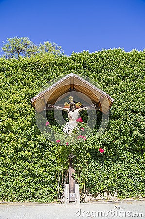 Jesus christ, wooden crucifix, spontaneous religiosity of the people in the midst of plants and roses Stock Photo