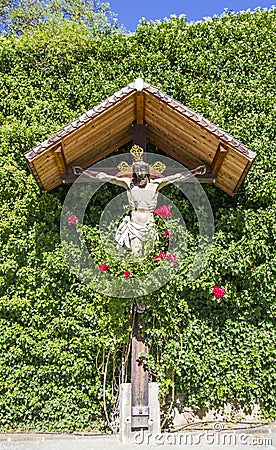 Jesus christ, wooden crucifix, spontaneous religiosity of the people in the midst of plants and roses Stock Photo