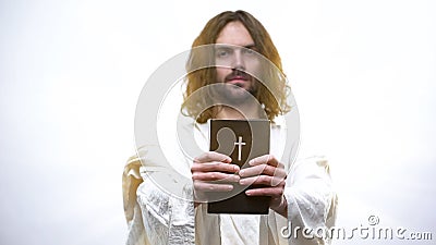 Jesus giving Holy Bible, calling for prayer, righteous living in catholicism Stock Photo