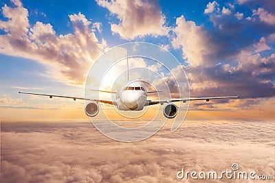 Jet airliner flies high in the clouds at dawn Stock Photo