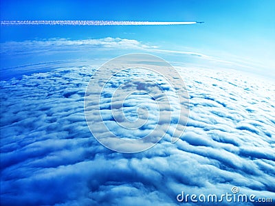 Jet plane contrail in blue sky above the clouds Stock Photo