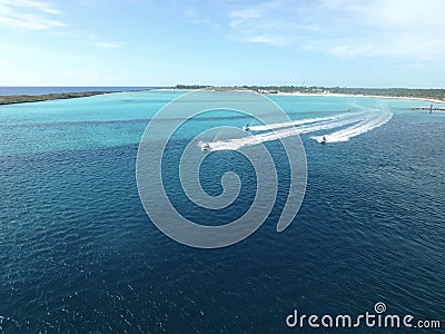 Jet skis traveling near an island in the Bahamas Stock Photo