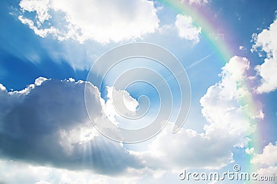 A jetliner aeroplane flying over white clouds towards a rainbow Stock Photo