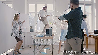 Jeune danse caucasienne heureuse de patron de société ainsi qu'avec des collègues, mouvement lent de célébration de succès Jeune danse caucasienne heureuse de patron de société ainsi qu'avec des collègues, mouvement lent de célébration de succès