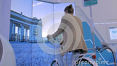 Jeune femme à l'aide de la machine interactive de simulateur de bicyclette Jeune femme à l'aide de la machine interactive de simulateur de bicyclette