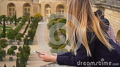 Jeune femme à l'aide du smartphone avec le fond de Versailles dans le mouvement lent clips vidéos Jeune femme à l'aide du smartphone avec le fond de Versailles dans le mouvement lent clips vidéos