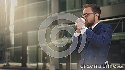 Jeune homme d'affaires barbu parlant au téléphone, café potable se tenant sur la rue de ville banque de vidéos Jeune homme d'affaires barbu parlant au téléphone, café potable se tenant sur la rue de ville banque de vidéos