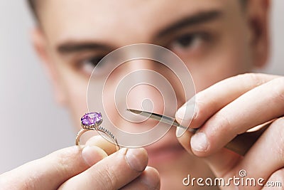 Jeweler inspects a gold ring with a large amethyst Stock Photo