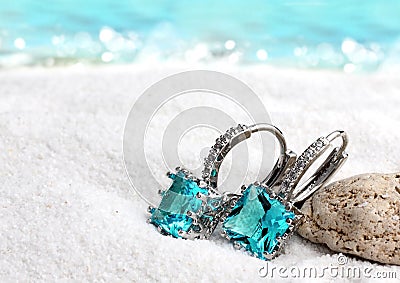 Jewelry earrings with aquamarine on sand beach background, soft Stock Photo