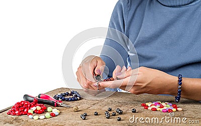 Jewelry making. Making bracelet from multi-colored beads on a rough wooden Stock Photo