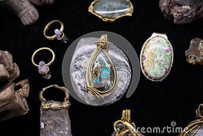 A jewelry necklace made with stone is surrounded by rings and other jewels Stock Photo