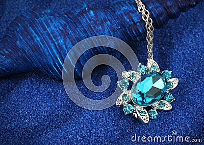 Jewelry pendant with gems on dark blue sand background Stock Photo