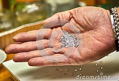 Jewelry production. Fixer holds diamonds on the palm before fixing Stock Photo
