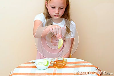 Jewish child dipping apple slices into honey on Rosh HaShanah. Stock Photo