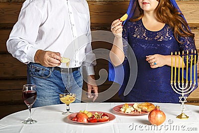 Jewish family, faceless husband and wife in Rosh Ashana at the festive table with burning candles I dip in honey. Stock Photo