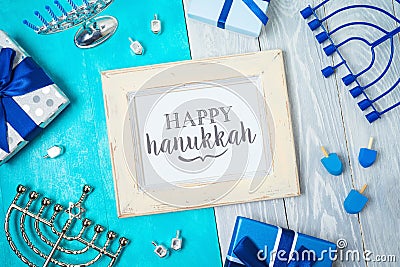 Jewish holiday Hanukkah greeting card with photo frame, menorah, gift box and spinning top on wooden table Stock Photo