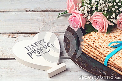 Jewish holiday Passover Pesah concept with matzoh, rose flowers and heart shape sign over wooden background Stock Photo