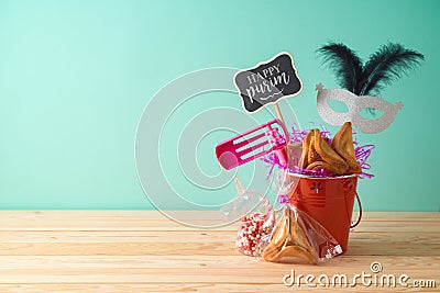 Jewish holiday Purim background with bucket, carnival mask, noisemaker and hamantaschen cookies on wooden table Stock Photo