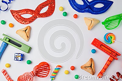 Jewish holiday Purim concept with hamantaschen cookies, carnival mask and noisemaker on white background. Stock Photo