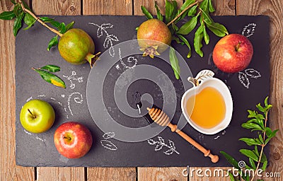 Jewish holiday Rosh Hashana background with apples, pomegranate and honey on blackboard. View from above. Stock Photo