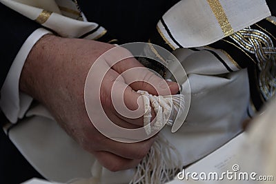 Holding tzitzit around the hand during Jewish prayer Stock Photo