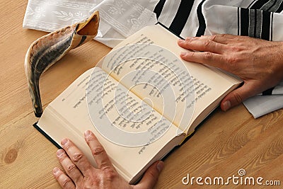 Jewish man hands holding a Prayer book, praying, next to tallit. Jewish traditional symbols. Rosh hashanah jewish New Year holida Stock Photo