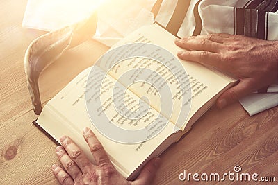 Jewish man hands holding a Prayer book, praying, next to tallit. Jewish traditional symbols. Rosh hashanah jewish New Year holida Stock Photo